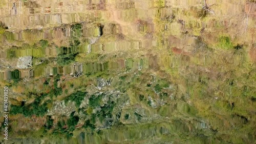 Reflection of mountain side covered with dry yellow grass in mountain lake. Sunny autumnn wamr day with nice weather. photo