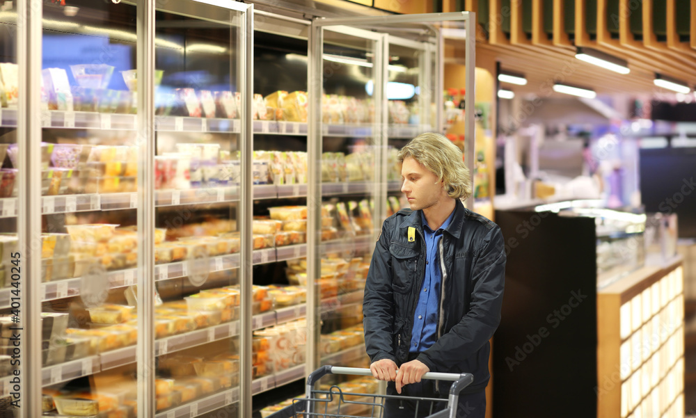 Woman choosing frozen food from a supermarket freeze.Supermarket shopping, face mask