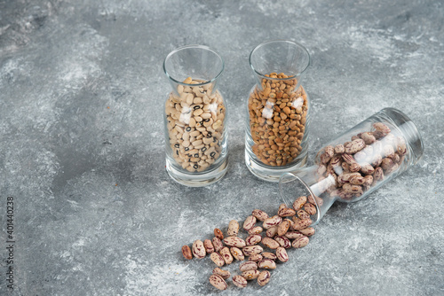 Three glasses of jar with unprepared beans on a gray background photo