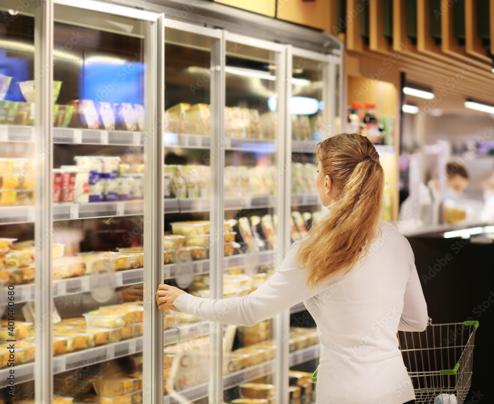 Woman choosing frozen food from a supermarket freezer.. Woman choosing frozen food from a supermarket freezer..