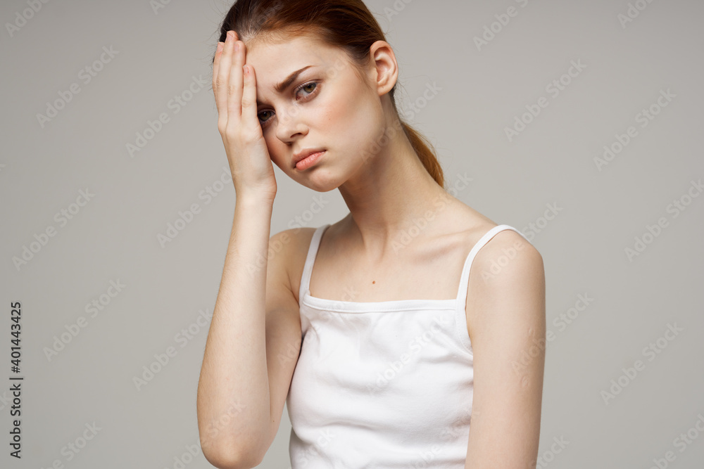 beautiful woman in white t-shirt touching face with hands on gray background health problems headache beautiful woman in white t-shirt touching face with hands on gray background health problems headache