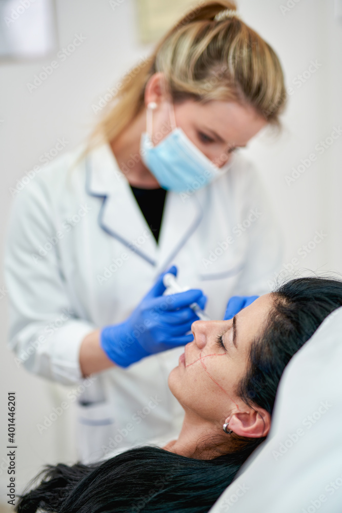 Close up of hands of cosmetologist making botox injection. She is holding syringe. Woman is receiving procedure with enjoyment. High quality photo Close up of hands of cosmetologist making botox injection. She is holding syringe. Woman is receiving procedure with enjoyment. High quality photo