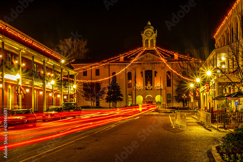 Historic Oxford Courthouse in the middle of town square with streaming head and tail lights at night. Christmas lights dominate.