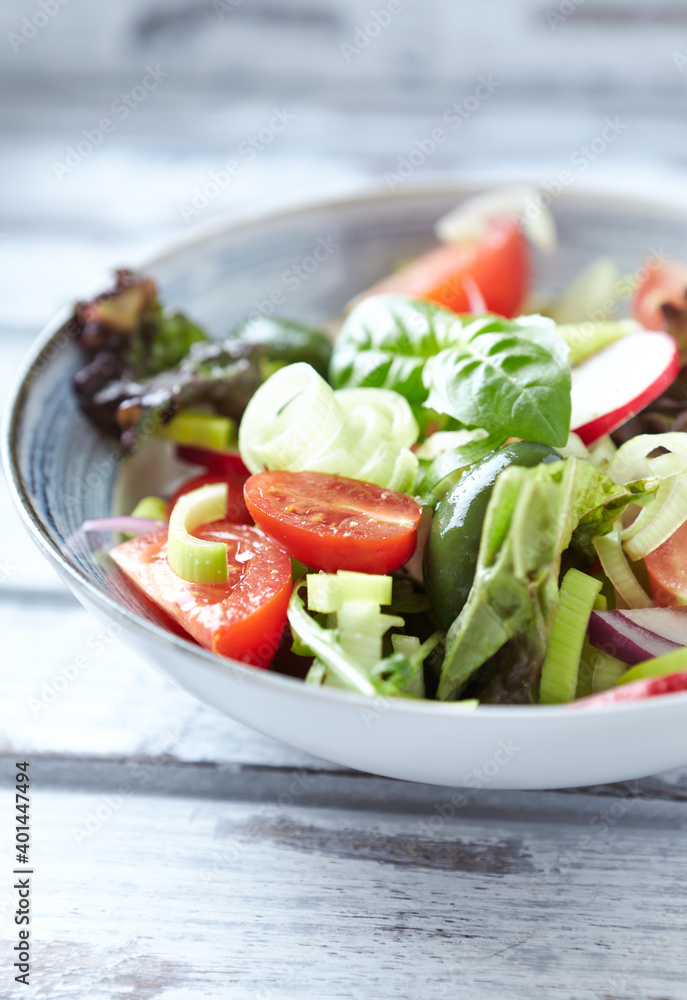 Salad with radish, green olives, tomatoes, cucumber and fresh basil. Bright wooden background. Close up. 