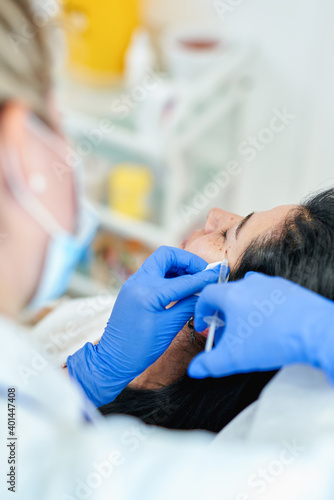 Close up of hands of cosmetologist making botox injection. She is holding syringe. Woman is receiving procedure with enjoyment. High quality photo