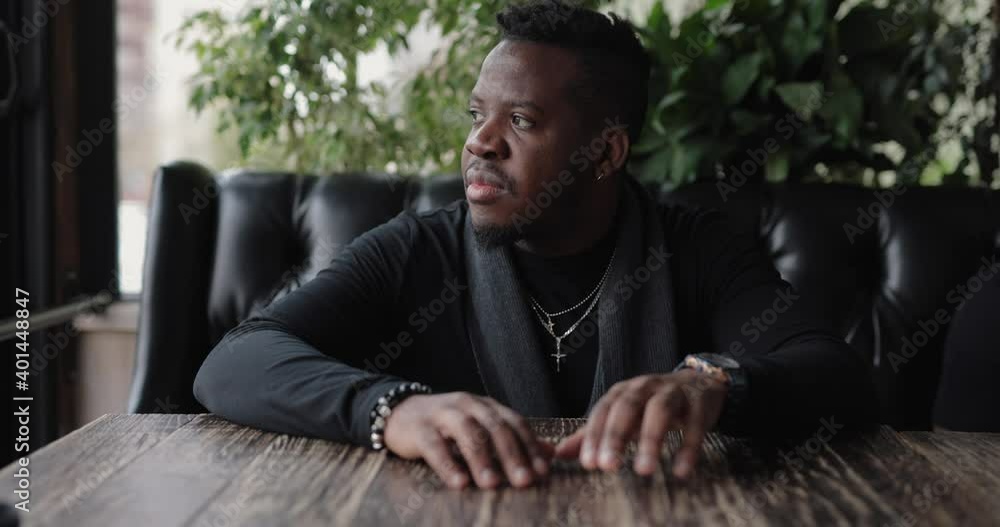 Confident African man sitting at the table waiting his food Confident African man sitting at the table waiting his food