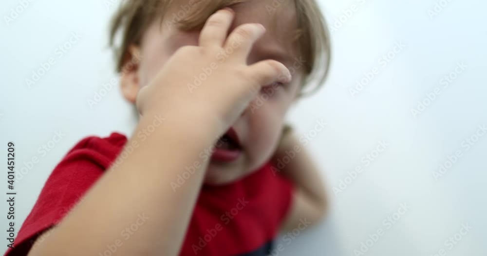 Tired toddler boy rubbing eye with hand. Sleepy baby child Tired toddler boy rubbing eye with hand. Sleepy baby child