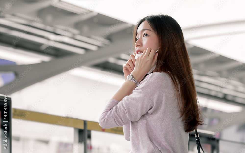 Asian woman wearing mask and standing at railway station
