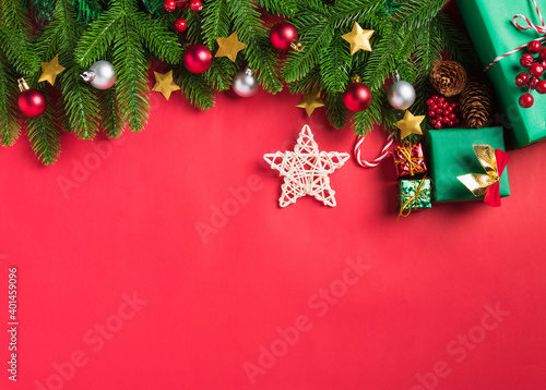 Christmas background presents greeting card with top view overhead green fir tree branches, decoration gift box and star, Xmas holiday celebration season on red table background with copy space