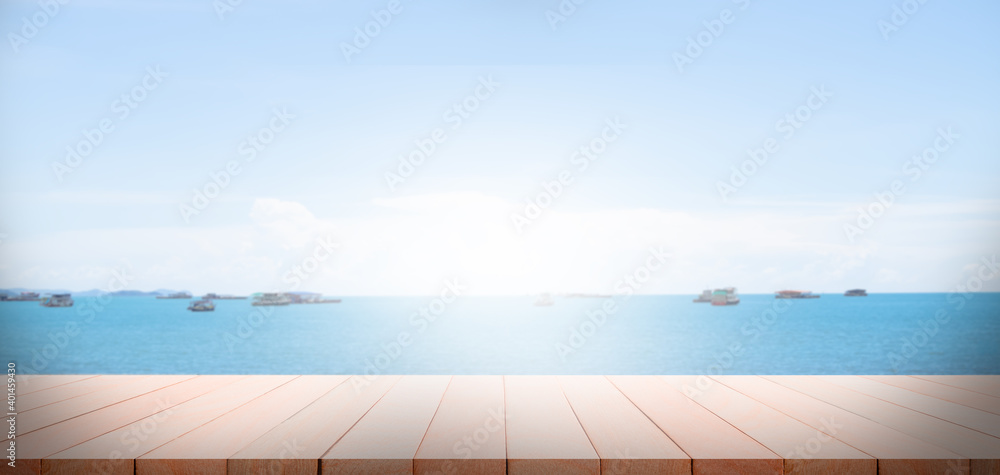 Wood perspective on sand beach with sea cocept. over light of old wood table on blur image of ocean with bokeh and sky. for travel summer holidays.