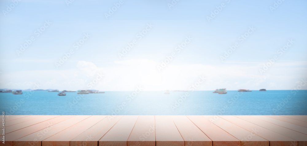 Fototapeta premium Wood perspective on sand beach with sea cocept. over light of old wood table on blur image of ocean with bokeh and sky. for travel summer holidays.