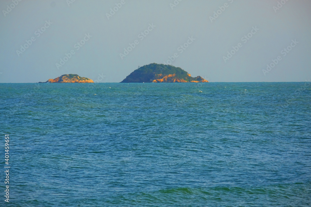 Twin islands in the sea on blue sky background Twin islands in the sea on blue sky background