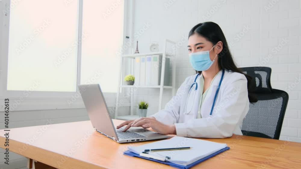asian woman doctor wear protection face mask work with computer laptop showing a patient information on digital tablet clip board, patient listen to specialist in clinic office, medical protect asian woman doctor wear protection face mask work with computer laptop showing a patient information on digital tablet clip board, patient listen to specialist in clinic office, medical protect