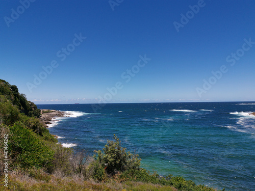 Stunning view of a deep blue sea and small beach from a coastal trail lookout, Sydney, New South Wales, Australia 