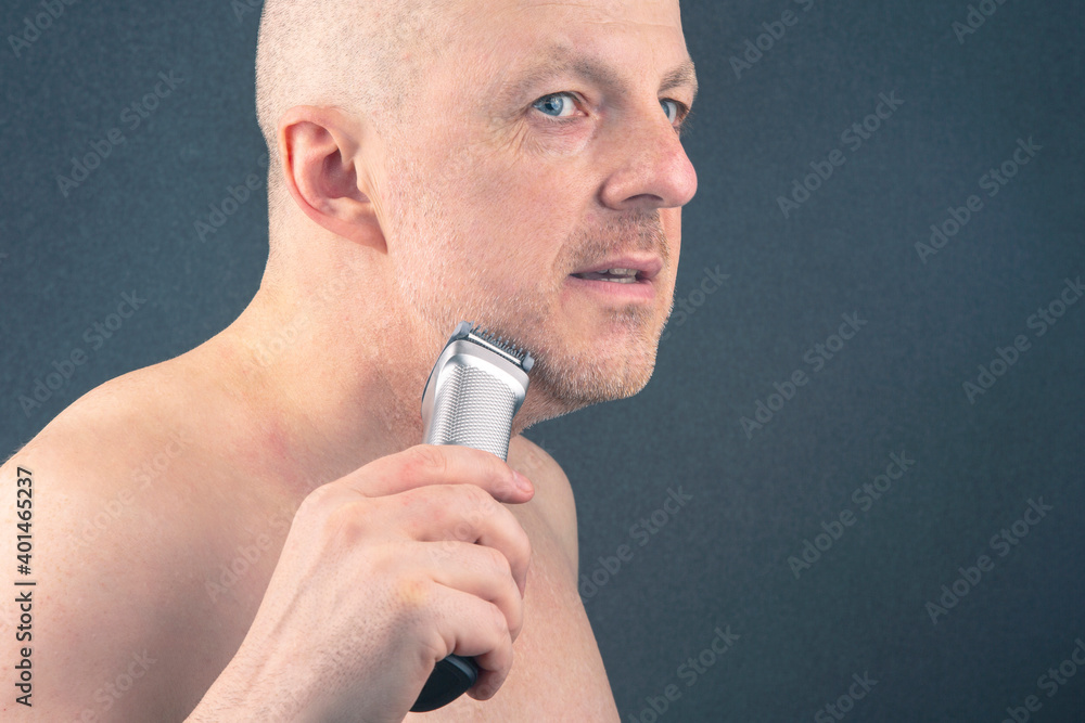 Bearded man with trimmer to adjust beard in hand. grooming and fashionable style barbershop. Beard length correction