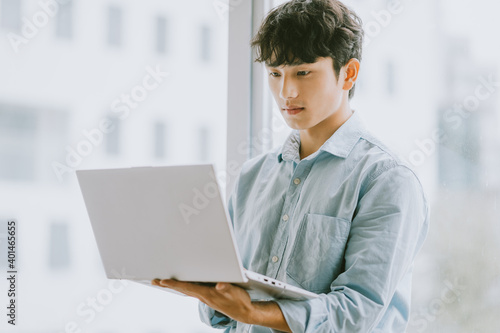 Asian businessman is using laptop to work by window photo