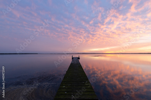 Colorful sunrise cloud over a wooden jetty on the lake.