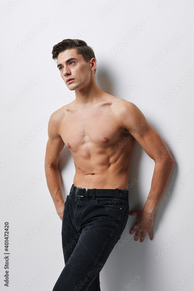 sporty man in jeans stands near the wall indoors