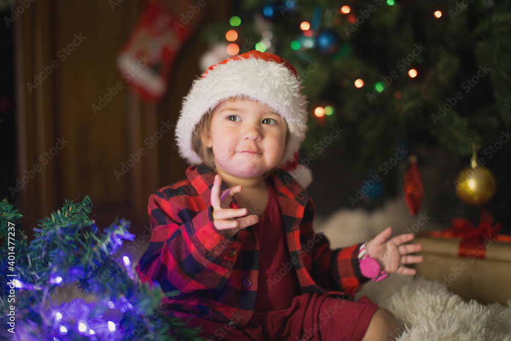 a child in red clothes is sitting waiting for the new year. the concept of celebrating Christmas at midnight. holiday costume a child in red clothes is sitting waiting for the new year. the concept of celebrating Christmas at midnight. holiday costume