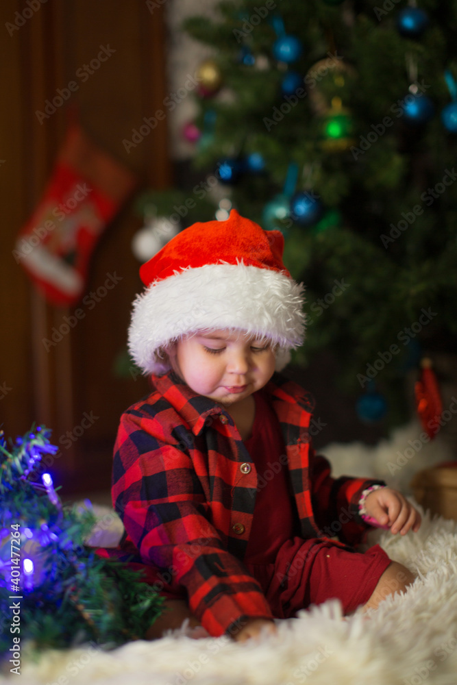 a child in red clothes is sitting waiting for the new year. the concept of celebrating Christmas at midnight. holiday costume a child in red clothes is sitting waiting for the new year. the concept of celebrating Christmas at midnight. holiday costume
