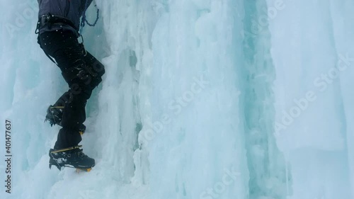 Crampons close-up on his feet ice climber on a frozen waterfall. Shards of ice.