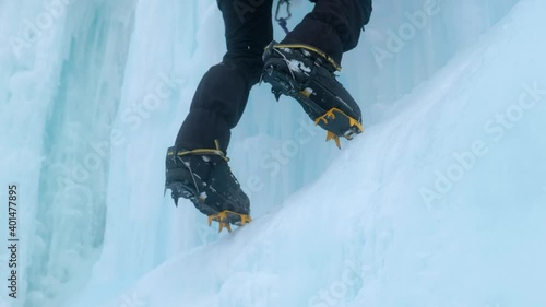 Crampons close-up on his feet ice climber on a frozen waterfall. Shards of ice.