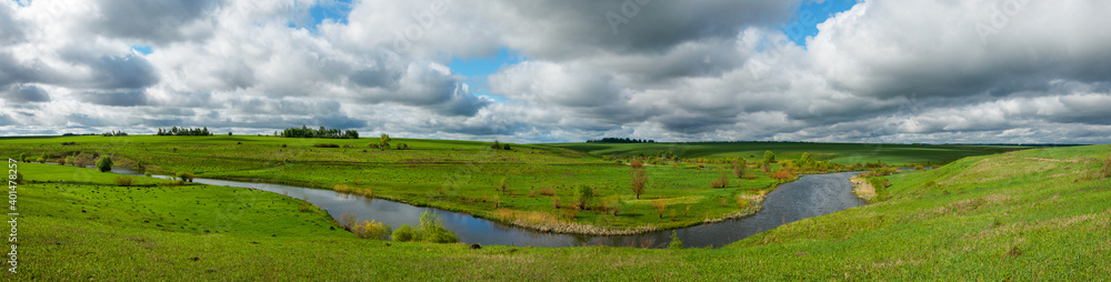 Spring panoramic rural landscape with river and green fields