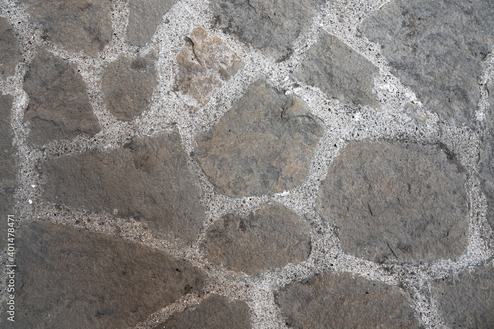 Stone pavement. Texture of stone paved ground. Large jagged stone blocks on a pedestrian sidewalk or road. Ancient masonry. Great for background and design. Stone pavement. Texture of stone paved ground. Large jagged stone blocks on a pedestrian sidewalk or road. Ancient masonry. Great for background and design.