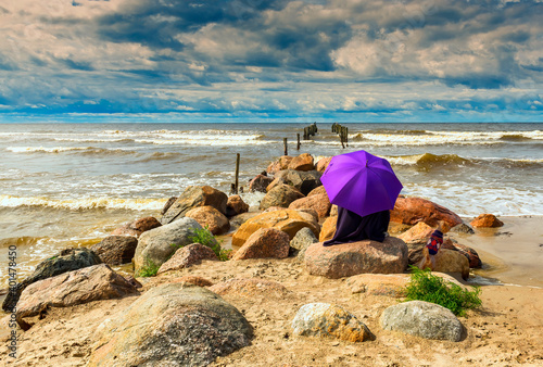 Lonely umbrella among stones of old broken pier on a beach of the Baltic Sea