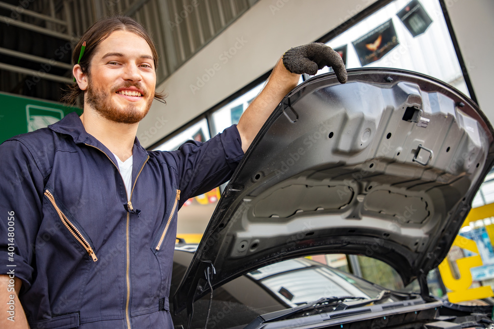 Handsome man mechanics in uniform is working in auto service with lifted vehicle and tablet. Car repair and maintenance. Maintenance and acceptance Handsome man mechanics in uniform is working in auto service with lifted vehicle and tablet. Car repair and maintenance. Maintenance and acceptance