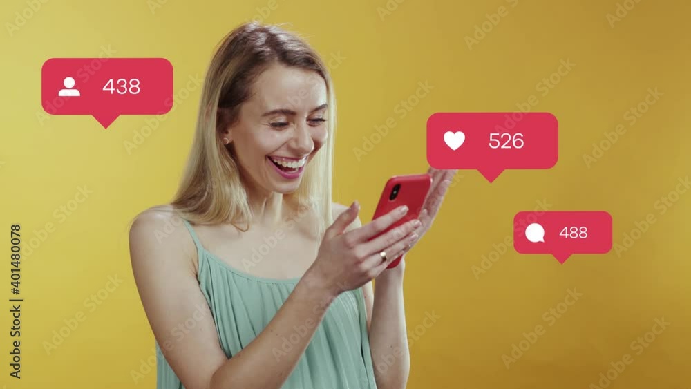 Happy cheerful caucasian blonde woman in casual clothes using smartphone feel much happy about likes and comments. Social media icons. User interface. Happy cheerful caucasian blonde woman in casual clothes using smartphone feel much happy about likes and comments. Social media icons. User interface.