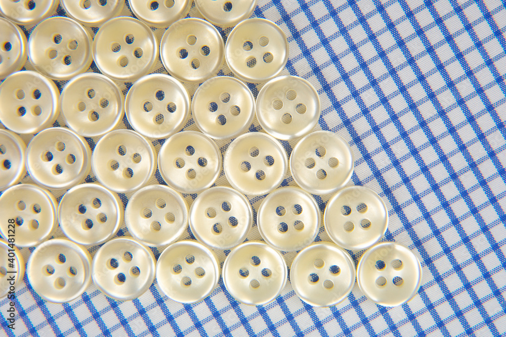 Obraz premium Plastic shiny buttons for clothes on a fabric background. Fashion and clothing. Factory industry