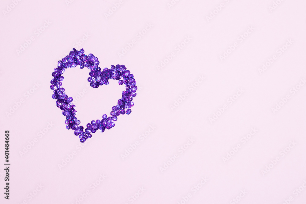 Purple sequins scattered in the form of heart on pink background. Valentine's Day. Free space for text