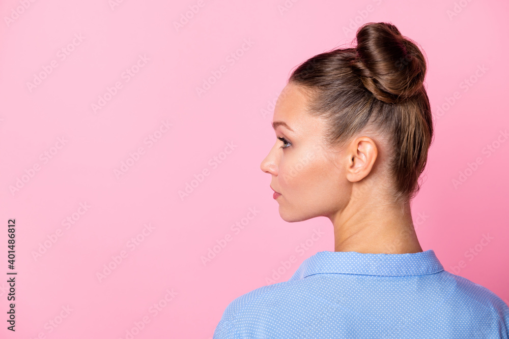 Rare view photo portrait of girl bun hairstyle looking at blank space serious confident isolated on pastel pink color background Rare view photo portrait of girl bun hairstyle looking at blank space serious confident isolated on pastel pink color background