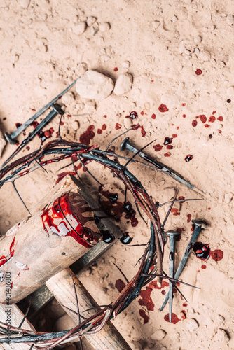Fotografia, Obraz Old wooden cross, hammer, bloody nails and crown of thorns on ground
