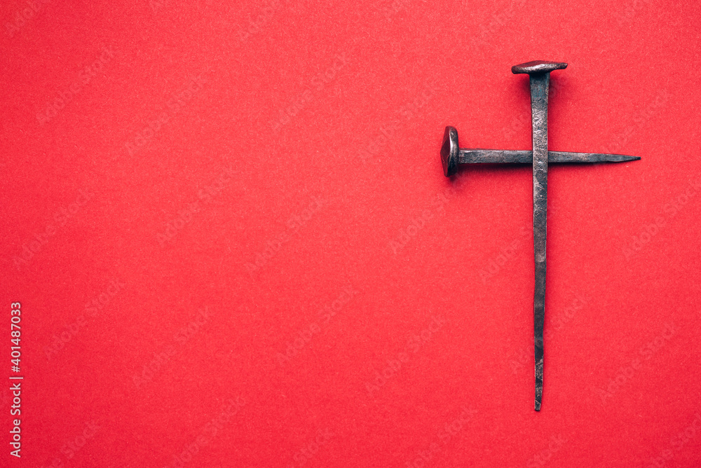 Cross made with rusty nails and drops of blood on red background. Copy space. Good Friday, Easter day. Christian backdrop. Biblical faith, gospel, salvation concept. Crucifixion of Jesus Christ