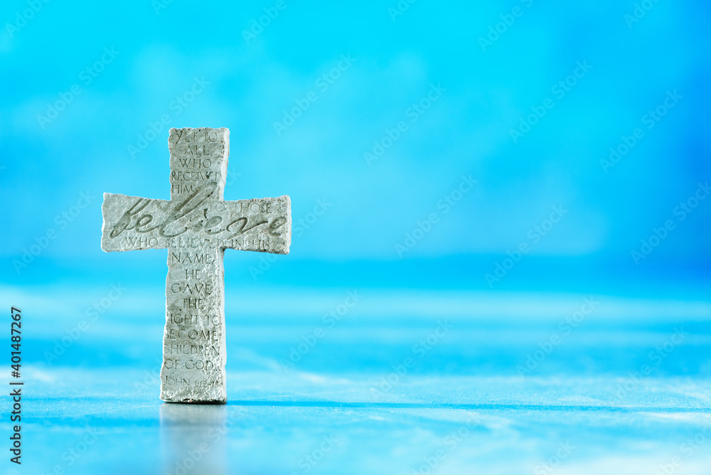 Stone cross with inscription Believe on blue background, Copy space. Christian backdrop. Biblical faith, gospel, salvation concept. Banner Stone cross with inscription Believe on blue background, Copy space. Christian backdrop. Biblical faith, gospel, salvation concept. Banner