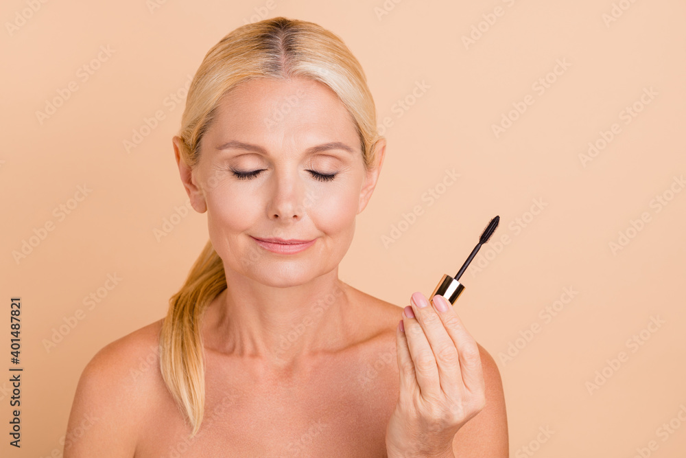 Close-up portrait of attractive blonde peaceful lady with using new black mascara closed eyes isolated over beige pastel color background