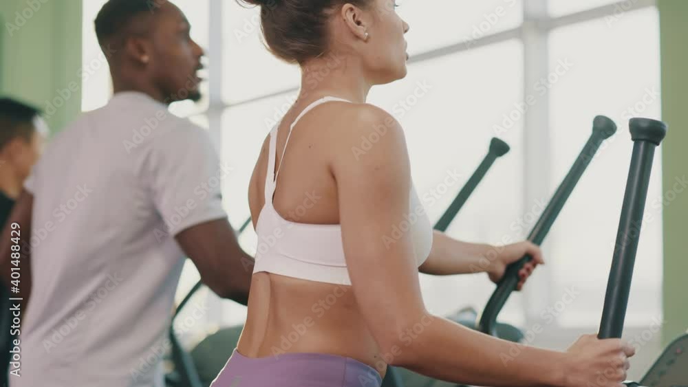 Attractive fitness woman with multi-ethnic people training at gym. Diverse young athletic muscular people working out cross trainers. Sport activity. Treadmill. Attractive fitness woman with multi-ethnic people training at gym. Diverse young athletic muscular people working out cross trainers. Sport activity. Treadmill.