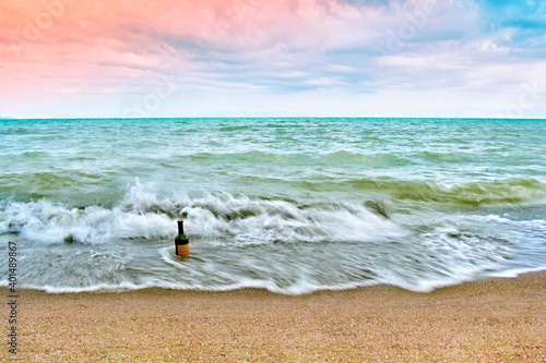 Fototapeta Naklejka Na Ścianę i Meble -  A Bottle of red dry wine on the beach in a sunrise