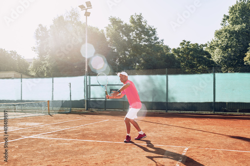 Middle-aged man playing tennis on outdoor tennis filed © fotofabrika