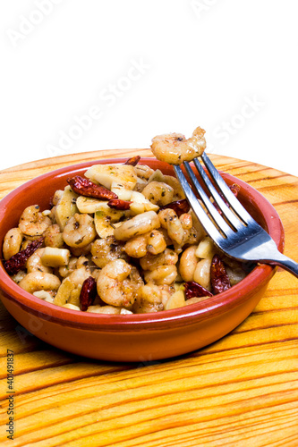 Prawns with garlic and cayenne in a ceramic bowl on a wooden tray