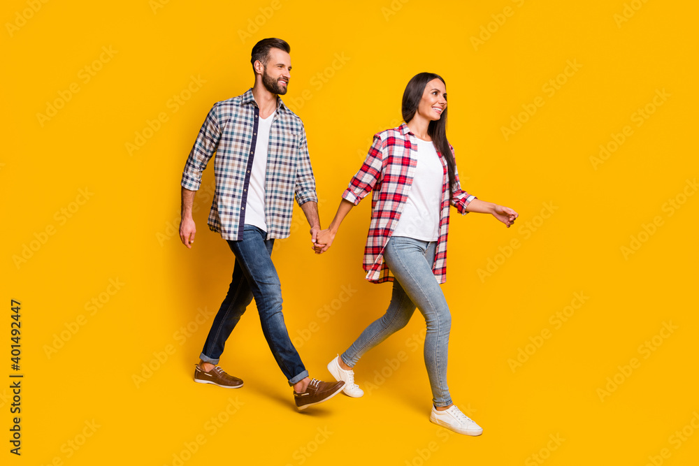 Photo portrait full body view of husband and wife holding hands walking isolated on vivid yellow colored background