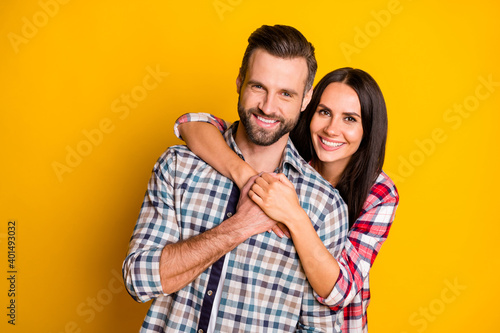 Portrait of lovely cute tender cheerful affectionate couple embracing isolated over bright yellow color background