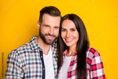 Portrait of two lovely tender cheerful amorous people embracing isolated over bright yellow color background