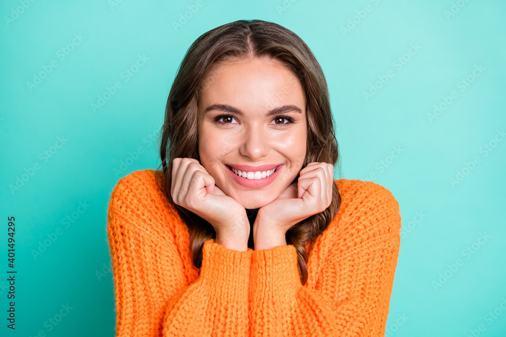 Portrait of young lovely pretty smiling cheerful girl in knitted orange sweater isolated on turquoise color background Portrait of young lovely pretty smiling cheerful girl in knitted orange sweater isolated on turquoise color background