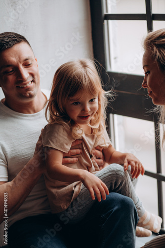 Photoshoot of a happy young family. Dad, mom and daughter. Studio photography.
