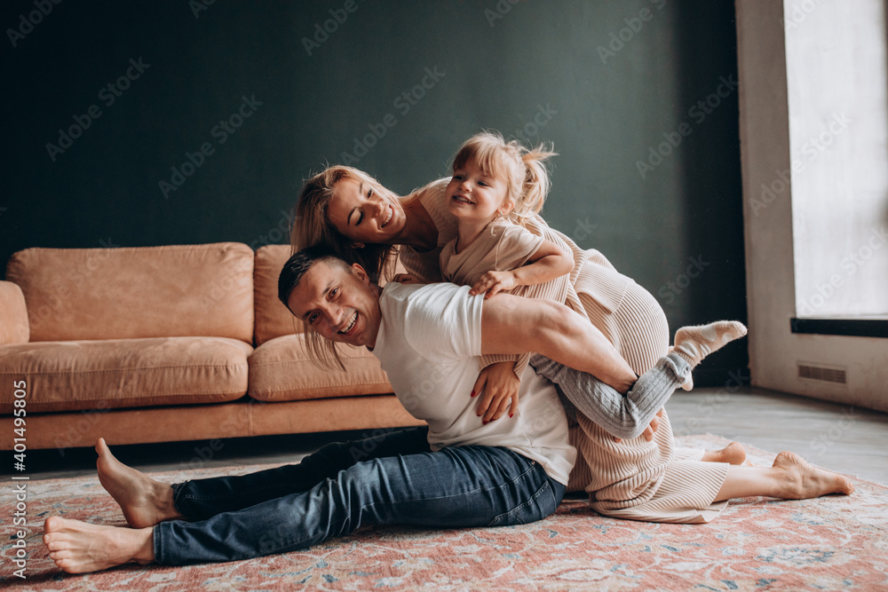 Photoshoot of a happy young family. Dad, mom and daughter. Studio photography.