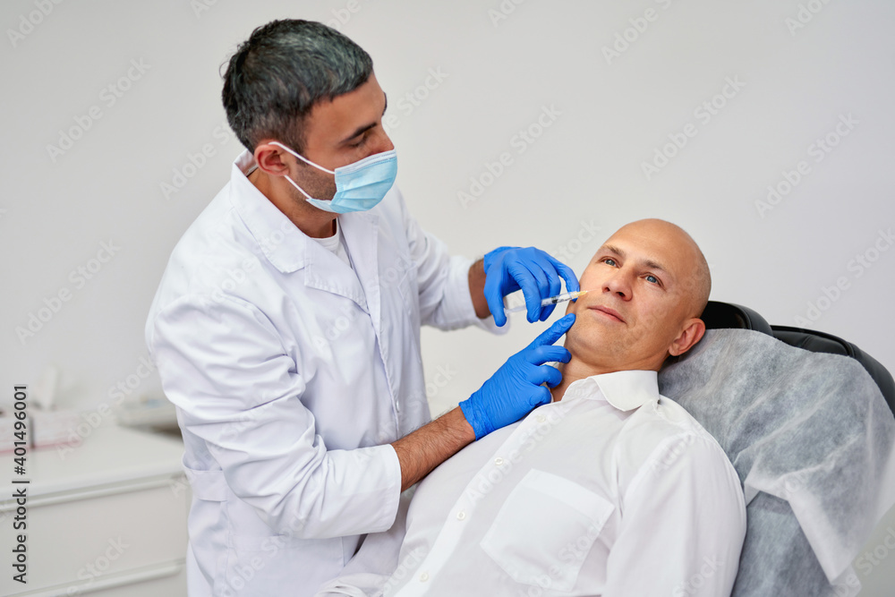 Cosmetologist making botox injection. Holding syringe. Man is receiving procedure with enjoyment Cosmetologist making botox injection. Holding syringe. Man is receiving procedure with enjoyment