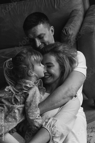 Photoshoot of a happy young family. Dad, mom and daughter. Studio photography. Black and white photo.